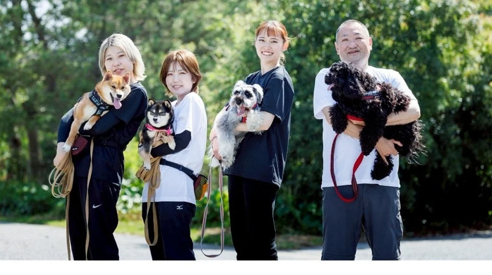 屋外で愛犬を抱きかかえ笑顔で並ぶ人々の集合写真