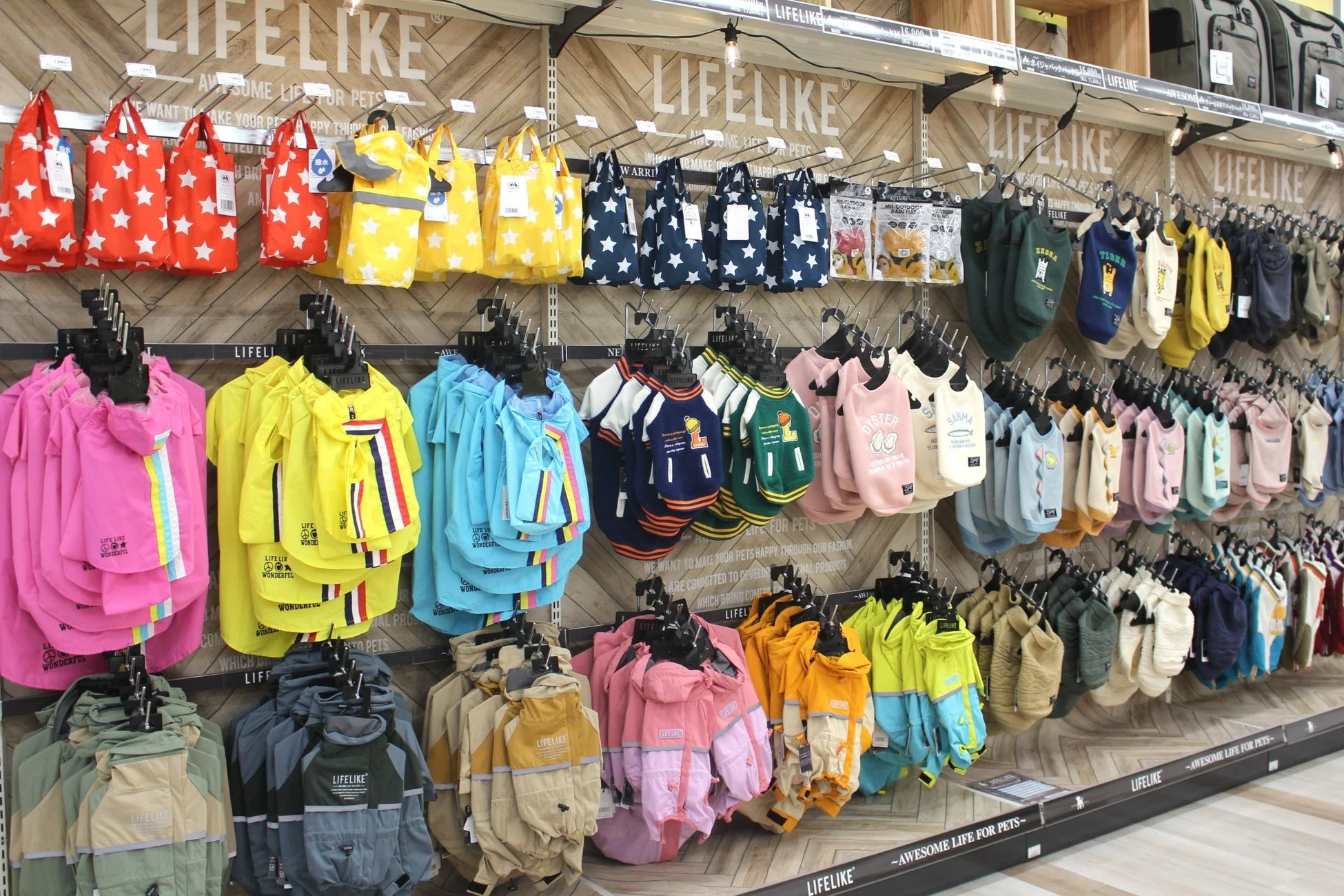 ペット用品店のディスプレイ棚に、LIFELIKEブランドのカラフルな犬用レインコートなどが豊富に展示。