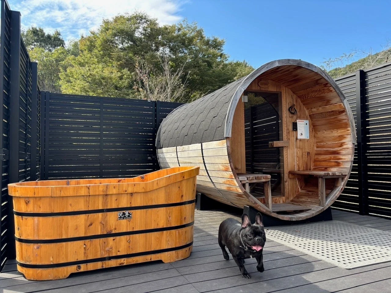 屋外に設置されたバレルサウナと木製の浴槽があるリラックススペース