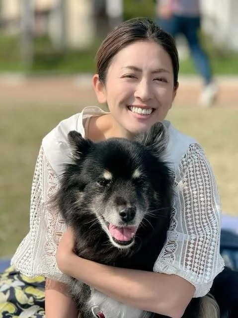 笑顔の女性が黒い犬を抱きかかえている心温まる写真