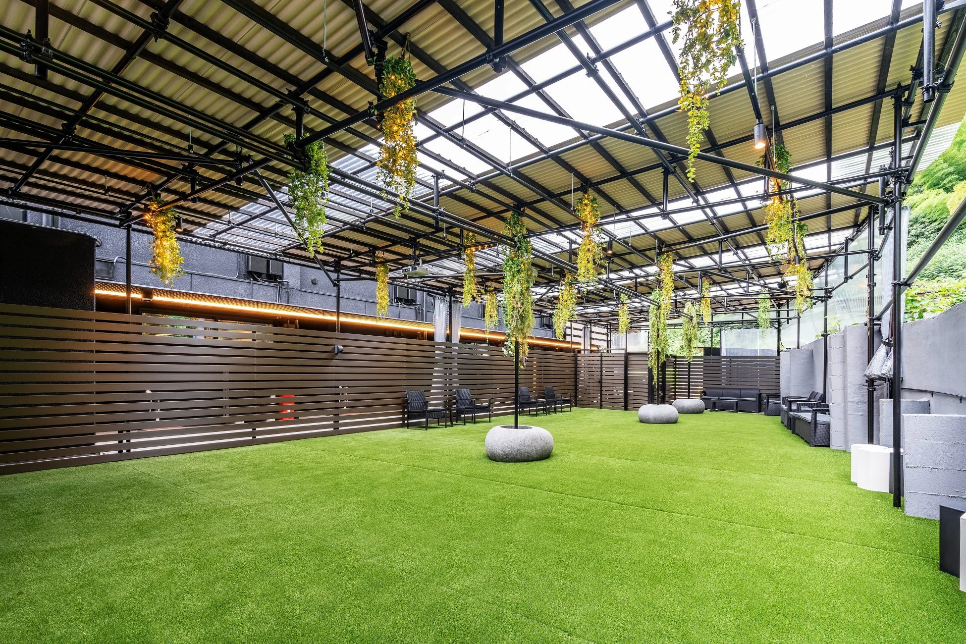 人工芝が敷かれた広々とした屋根付きの屋外空間